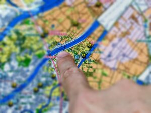 Close-up of a finger pointing to a location on a colorful printed map showing rivers and streets