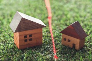 Two wooden toy houses on green grass with a red string running between them, like a playful outdoor setup.